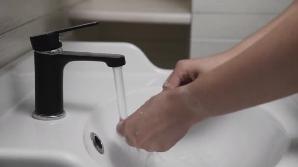 Banyoda diş fırçasıyla diş fırçalayan genç bir adam. Diş fırçaladıktan sonra fırçayı temizleyen ellerin yakın çekimi — Stok video