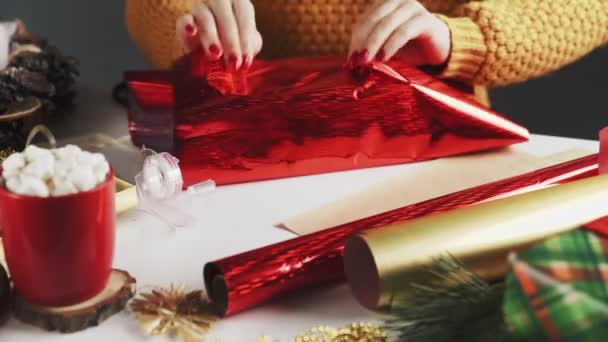 Женщина обертывает рождественский подарок в красную бумагу — стоковое видео