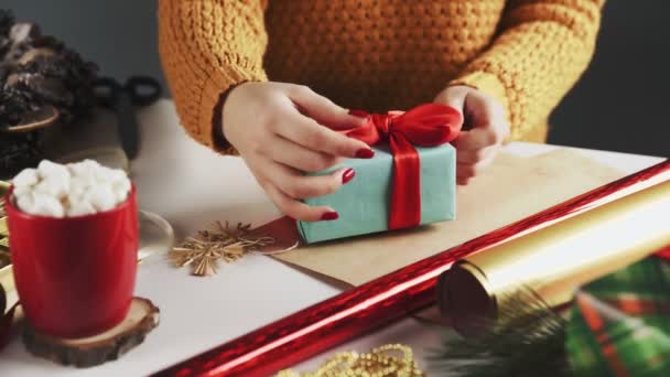 Mujer irreconocible desenvolviendo regalos de Navidad en la mesa con decoración de Navidad . — Vídeos de Stock