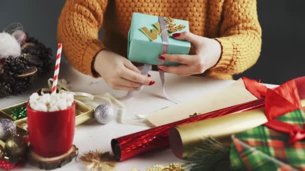 Vrouwelijke handen wikkelen kerstcadeau in blauw papier en strik lint — Stockvideo