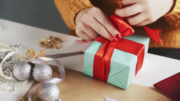 Close-up van vrouw koppelverkoop rood lint op kerstcadeau — Stockvideo