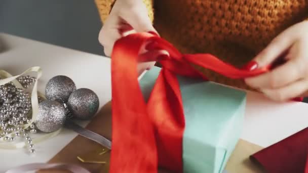 Close-up van vrouw koppelverkoop rood lint op kerstcadeau — Stockvideo