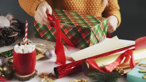 Onherkenbare vrouw bindt rood lint op kerstcadeau — Stockvideo