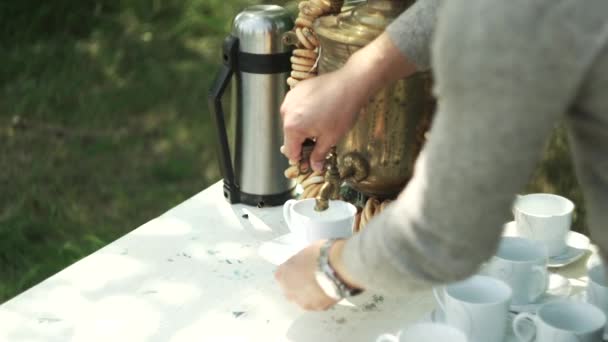 Женщина наливает кипяток из самовара в чашу — стоковое видео