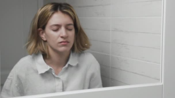 Ung sömnig kvinna tvättar ansiktet och torkar den med en handduk i ett badrum — Stockvideo