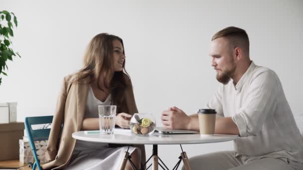 Un par de colegas felices hablando y coqueteando mientras están sentados en el comedor en la oficina durante el descanso del café — Vídeo de stock