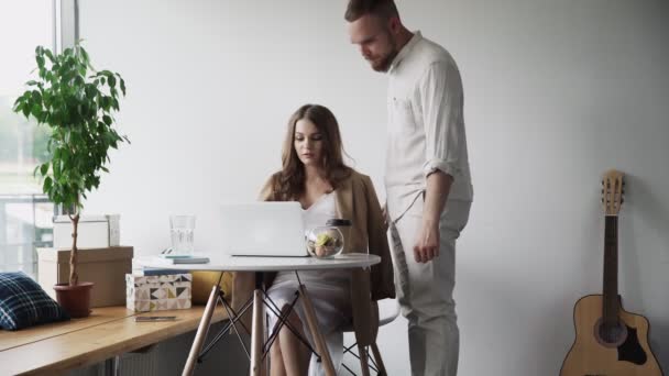 Επιχειρηματίας και γυναίκα εργάζονται μαζί. Ο άντρας φέρνει καφέ στη γυναίκα συνάδελφό του. — Αρχείο Βίντεο