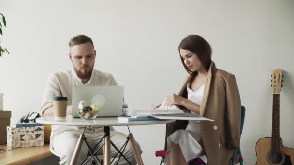 Empresario trabajando en cuaderno y Empresaria trabajando con documentos en coworking — Vídeos de Stock