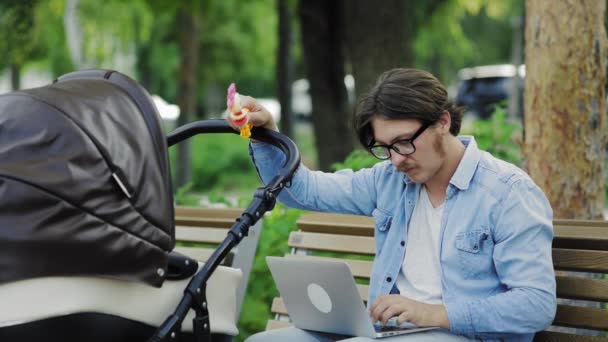 Freelancer sending laptop email and swinging stroller, family and career balance — Stock Video