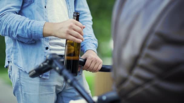 Close-up van mans hand met bier en kinderwagen in het park — Stockvideo