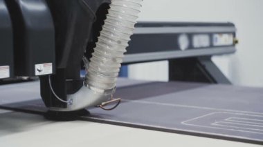 Bir endüstriyel testere ve vakum makinesi bir fabrikada plastikten parçalar kesiyor..