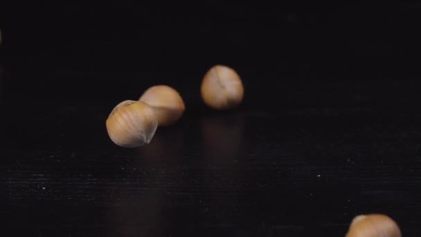 Hazelnuts are falling down on a black surface — Stock Video