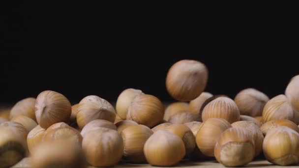 Hasselnötter faller ner på en svart yta. — Stockvideo