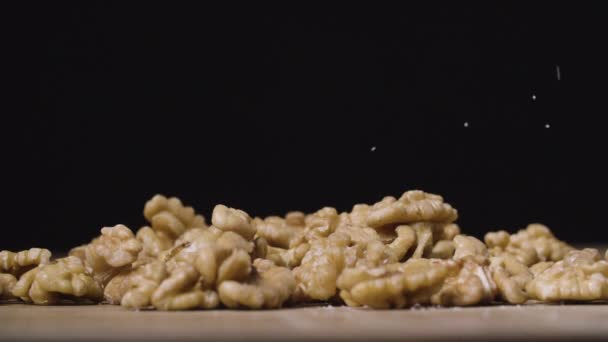 Соль падает на грецкие орехи. черный фон — стоковое видео