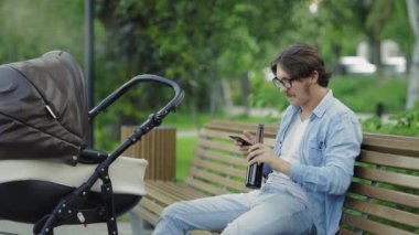 Babamın bebek arabasının yanında bira içerken ve telefon kullanırken görüntüsü.