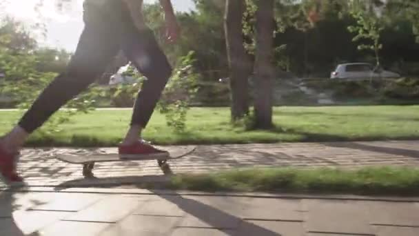 Yound Man korcsolyázik a parkban egy napsütéses napon — Stock videók