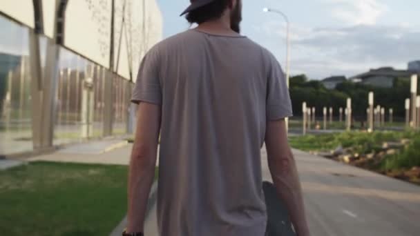 Вид на скейтбордиста, идущего со скейтбордом в парке — стоковое видео