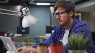 Ofisteki bilgisayarda çalışan programcının yan görünümü