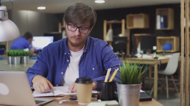 Молодой человек пишет заметки на липких разноцветных наклейках ручкой — стоковое видео