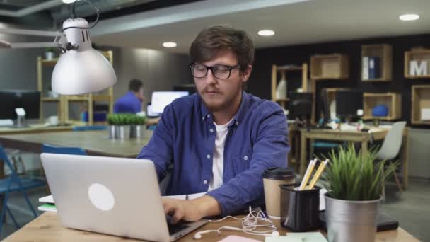 Jeune homme travaille sur un ordinateur et regarde le téléphone — Video