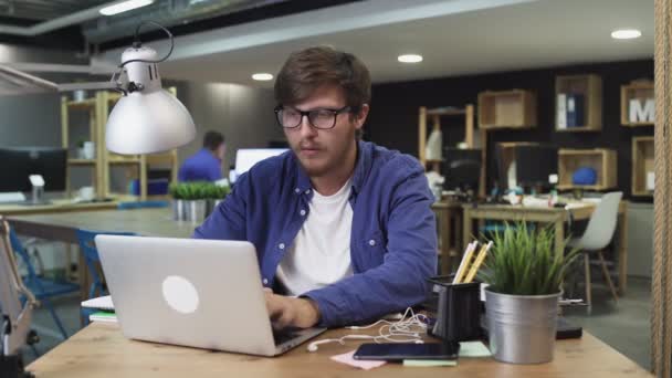 Assistent brengt koffie naar jonge baas terwijl hij werkt op laptop — Stockvideo