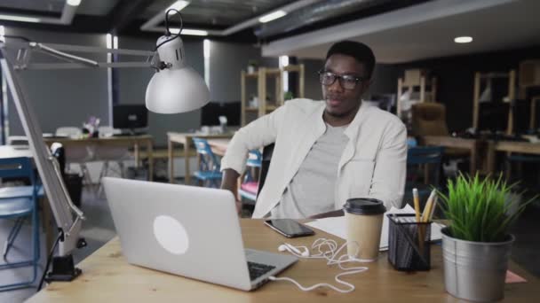 Dolly mossa di giovane uomo africano sta guardando video e sorridente — Video Stock