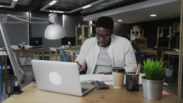 Hombre africano cansado esperando fin de día de trabajo en la oficina moderna — Vídeo de stock