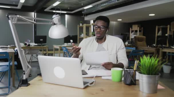 Afrikaner mit Kopfhörern führen Videokonferenz-Gespräch in modernem Büro — Stockvideo