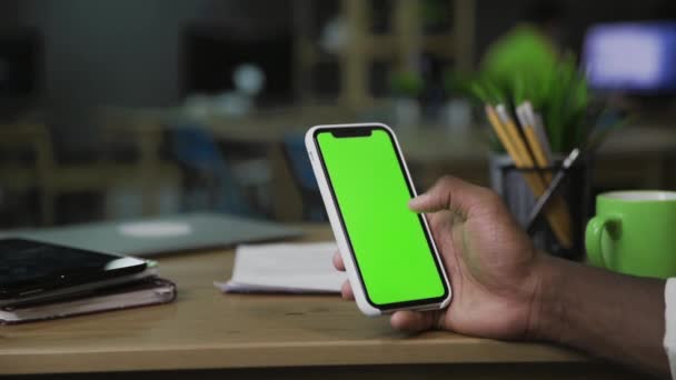 緑の画面で携帯電話を使用してネットサーフィンアフロ男のバッククローズアップビュー. — ストック動画