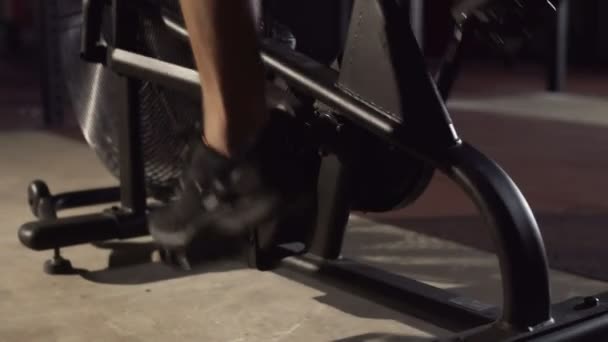 在体育馆里，穿着便衣的男子脚踏着运动服在跑车上旋转踏板 — 图库视频影像