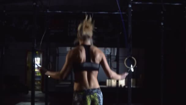 Athletic Beautiful Woman bär sportkläder övningar med hoppa rep i Hardcore Gym. — Stockvideo