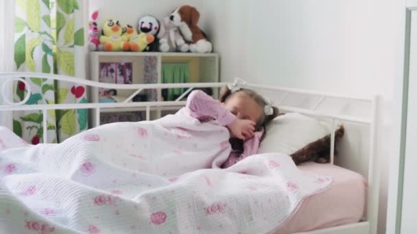 Mignonne petite fille enfant se réveille du sommeil dans le lit le matin . — Video