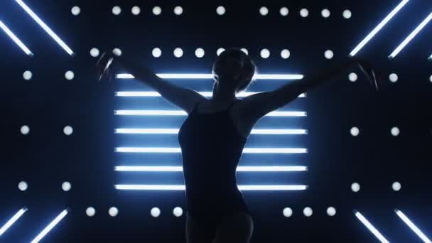 Meisje danst een sexy dans in een donkere kamer. Licht van achteren — Stockvideo