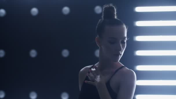 Mädchen tanzt einen sexy Tanz in einem dunklen Raum. Licht von hinten — Stockvideo