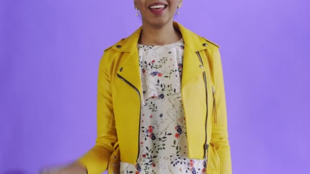 Parası olan tatmin olmuş Afro-Amerikalı kadın mor arka planda baş parmağını gösteriyor. Sarı ceket. — Stok video
