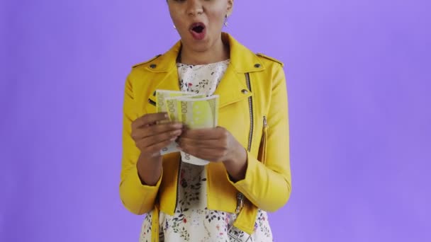 Attractive Afro american woman is counting money against a purple background Yellow jacket — 비디오