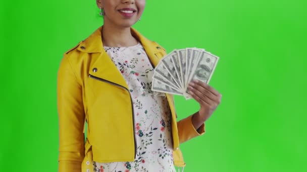 Retrato de mujer afroamericana con abanico de dinero sobre fondo verde en Studio. Chaqueta amarilla — Vídeos de Stock