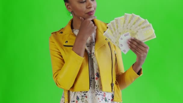 Στοχαστική επιτυχημένη αφροαμερικανή γυναίκα με χρήματα ανεμιστήρα στο πράσινο φόντο στο στούντιο. Κίτρινο σακάκι — Αρχείο Βίντεο