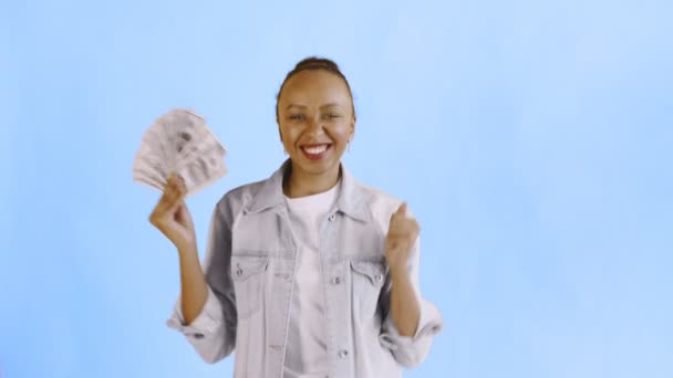 Ικανοποιημένος χαρούμενος ενθουσιασμένος αφρικάνος Αμερικανός γυναίκα δείχνει τα χρήματα και λέγοντας Ναι στο μπλε φόντο Jean σακάκι — Αρχείο Βίντεο