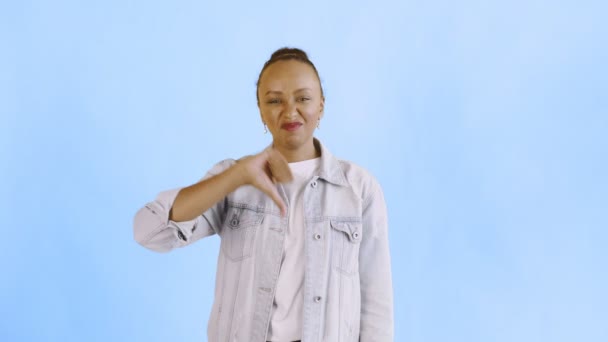 Νεαρή δυστυχισμένη Αφρο-Αμερικανίδα δίνει τον αντίχειρα κάτω στο μπλε φόντο Jean jacket — Αρχείο Βίντεο
