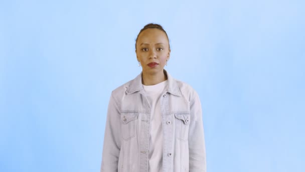 Prise de vue de femme afro-américaine regardant la caméra sur fond bleu veste Jean — Video