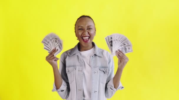 Satisfied happy excited african american woman showing money and saying O MY GOD on yellow background Jean jacket — Stock Video