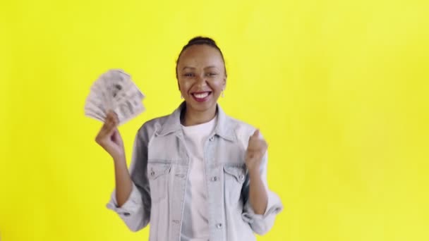 Satisfecho feliz emocionado mujer afroamericana mostrando dinero y diciendo YEAH sobre fondo amarillo chaqueta Jean — Vídeos de Stock