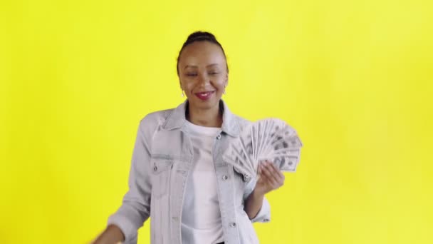 Satisfecho feliz emocionado mujer afroamericana mostrando dinero y bailando en cámara sobre fondo amarillo chaqueta Jean — Vídeos de Stock