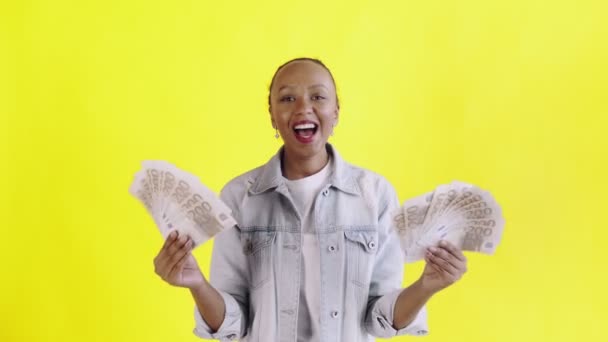 Удовлетворенный счастливый взволнованный африканский американец, показывая деньги и говоря о Боже мой на желтом фоне Жан куртка — стоковое видео