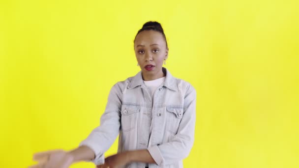 Retrato de niña afroamericana molesta perpleja mirando en cámara sobre fondo amarillo. Expresión facial de palma chaqueta Jean — Vídeos de Stock