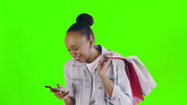 Portré afro-amerikai nő bevásárló táskák beszél okostelefonnal zöld háttér stúdió. Jean kabát — Stock videók