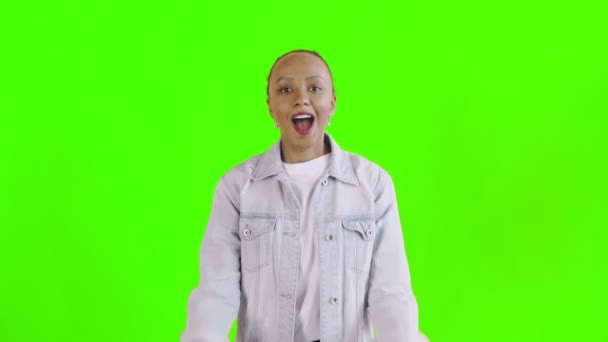 Beautiful happy african young woman surprised while looking at the camera and saying OH MY GOD on green background Jean jacket — Stock Video