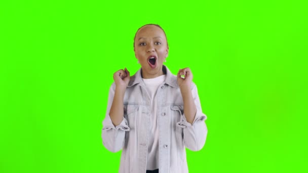 Gyönyörű boldog afrikai fiatal nő mondja Oh Istenem, és tánc zöld háttér Jean kabát — Stock videók