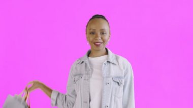 Alışveriş çantalı Afro-Amerikan kadın portresi Stüdyoda pembe arka planda baş parmak gösteriyor. Kot ceket.